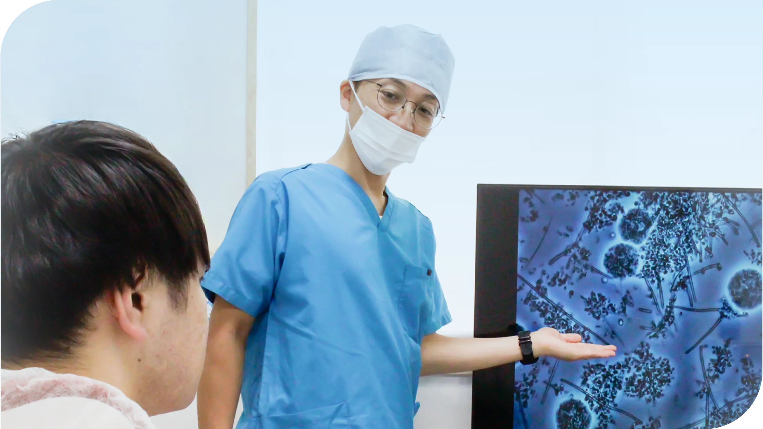 医師が顕微鏡画像をモニターで患者に説明している様子