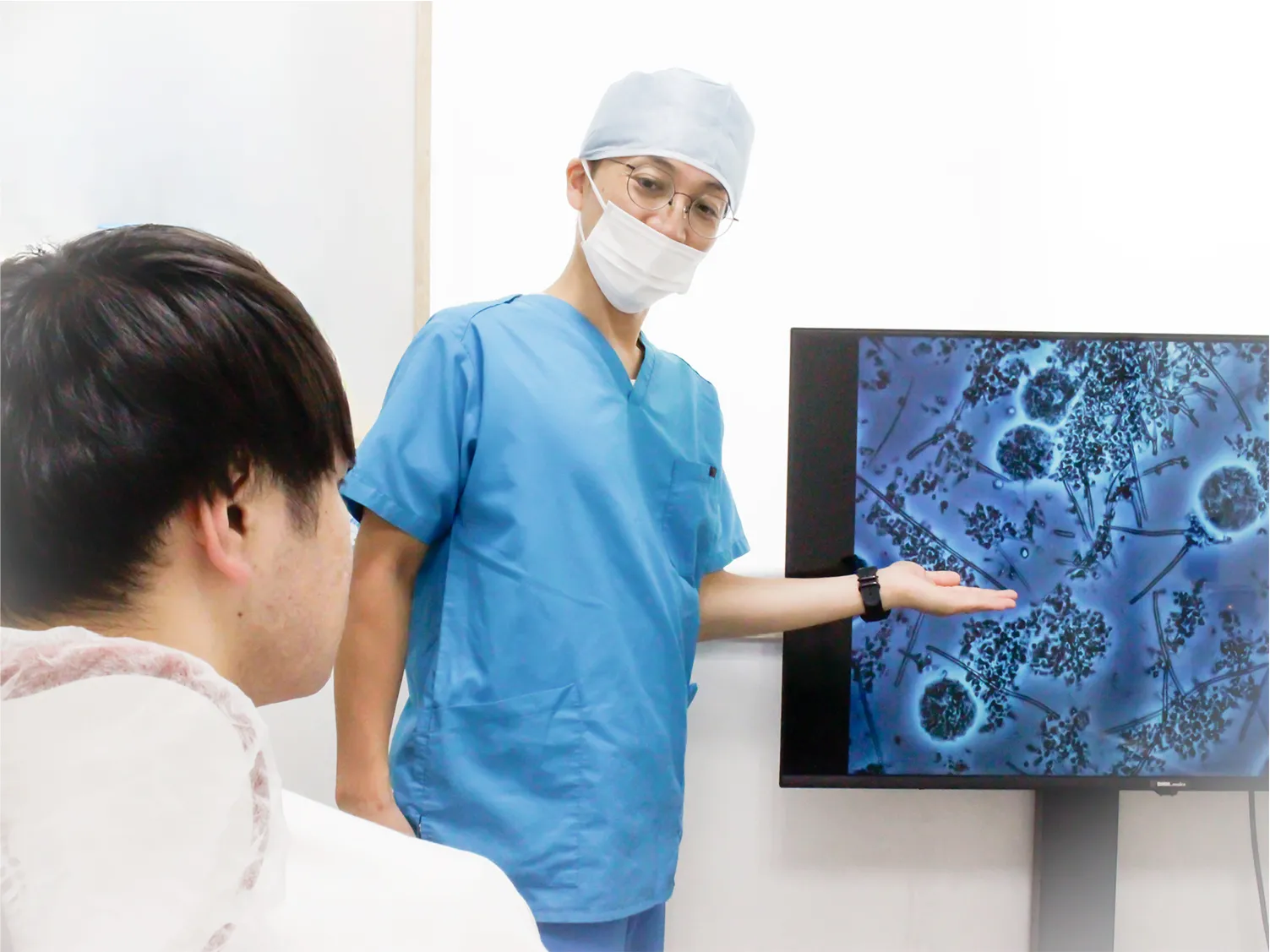 医師が顕微鏡画像をモニターで患者に説明している様子